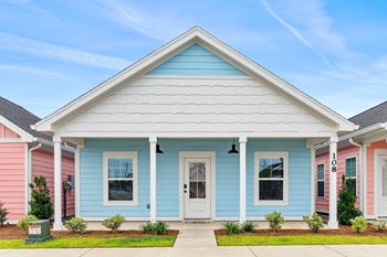a blue house with a white porch and pink and blue houses